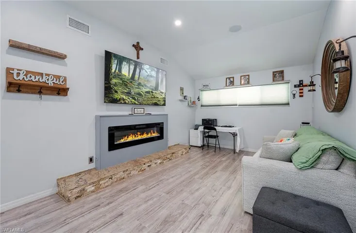 Living room with lofted ceiling and light wood-type flooring