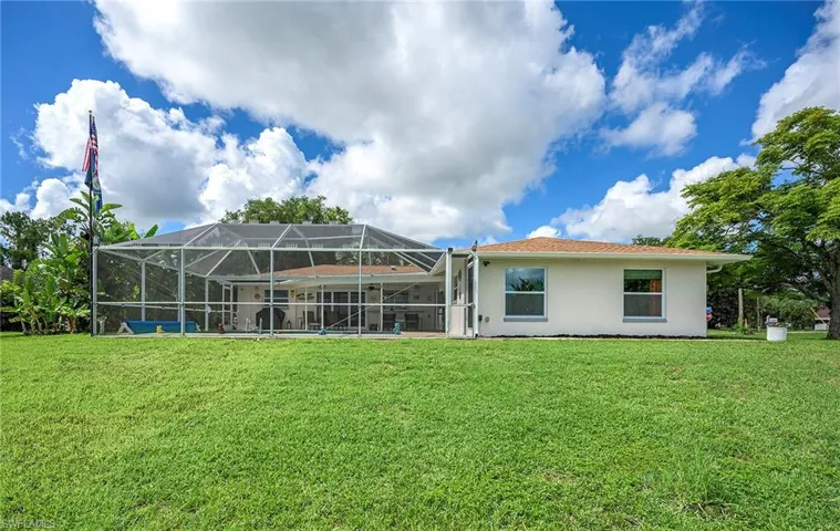 Rear view of property with glass enclosure and a lawn