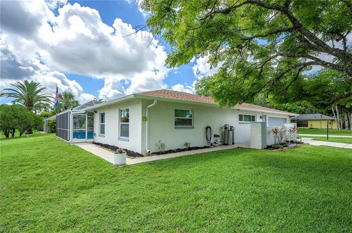 Back of property with a garage, a lawn, and glass enclosure