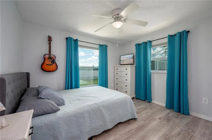 Bedroom featuring a textured ceiling, ceiling fan, and light wood-type flooring