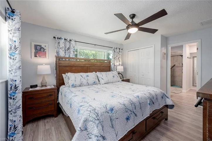 Bedroom featuring light hardwood / wood-style floors, a textured ceiling, a closet, ensuite bathroom, and ceiling fan