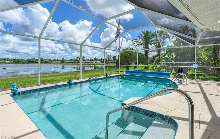 View of swimming pool with a patio, glass enclosure, and a water view