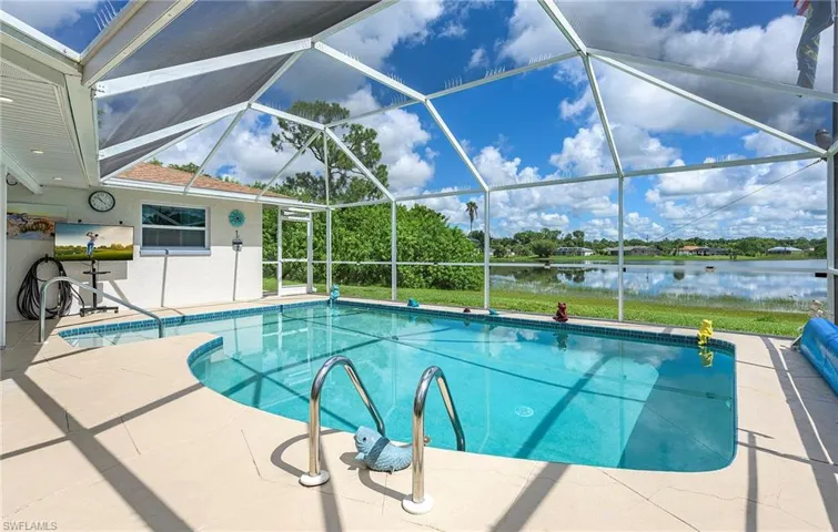 View of swimming pool with a patio, glass enclosure, and a water view