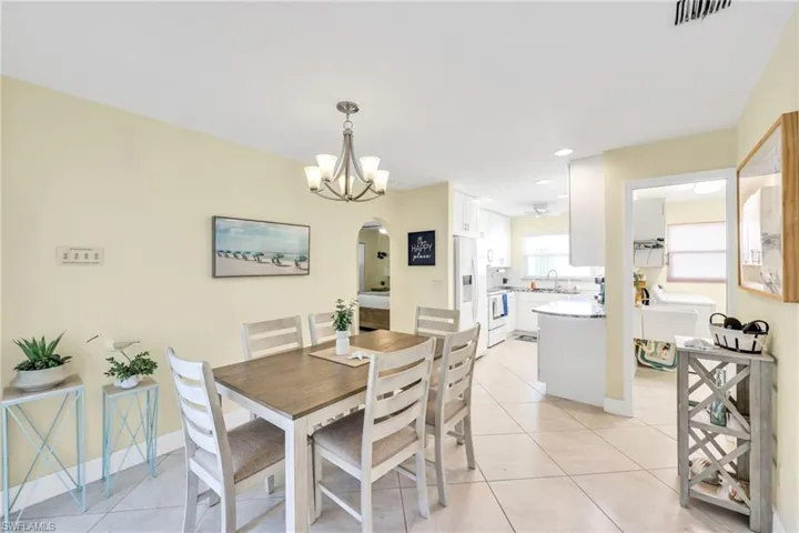 Dining area featuring light tile patterned floors, arched walkways, a chandelier, and recessed lighting