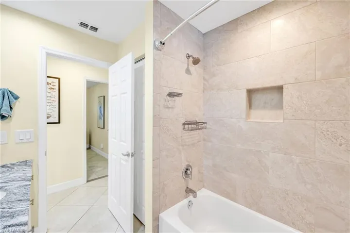 Bathroom with shower / washtub combination, vanity, and tile patterned flooring