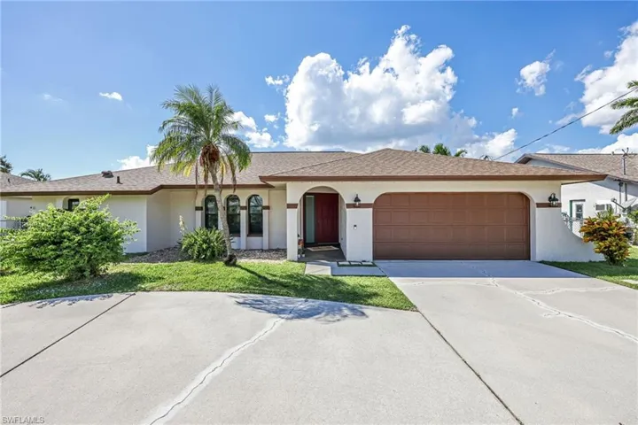 View of front of home featuring stucco siding, driveway, a front yard, and a garage