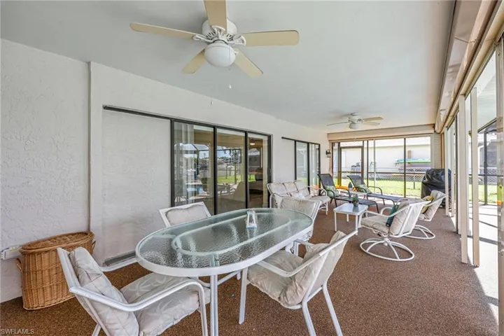 Sunroom featuring a textured wall, outdoor dining space, a ceiling fan, and carpet