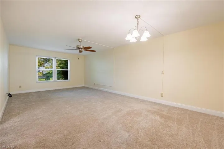 Living room featuring ceiling fan with notable chandelier and carpet