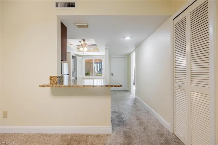 Kitchen peninsula and light colored carpet.