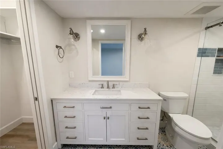 Bathroom with tiled shower, vanity, and a walk in closet