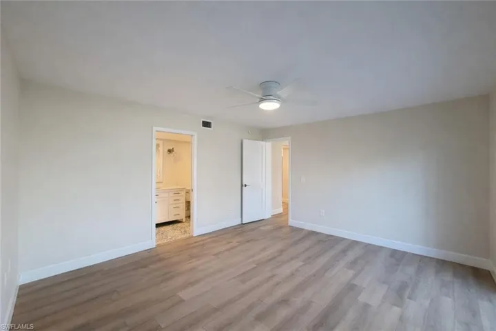 Unfurnished bedroom featuring light wood-type flooring, a ceiling fan, and ensuite bath