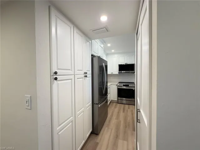 Kitchen featuring white cabinets, light wood-style flooring, appliances with stainless steel finishes, recessed lighting, and light countertops