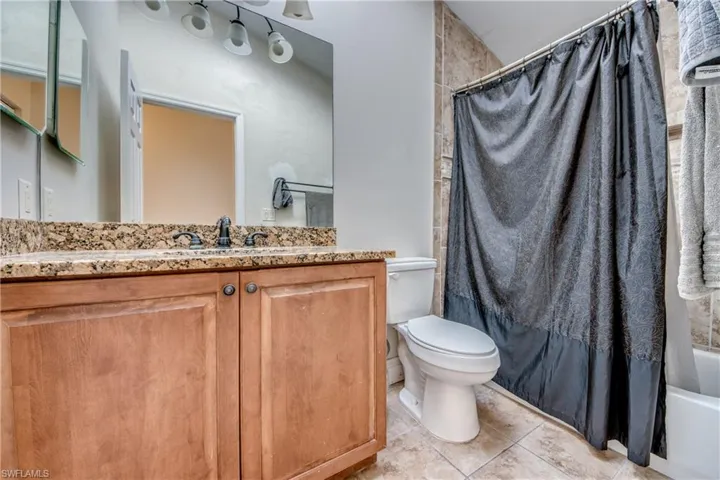 Full bath with shower / bath combo, vanity, and light tile patterned floors