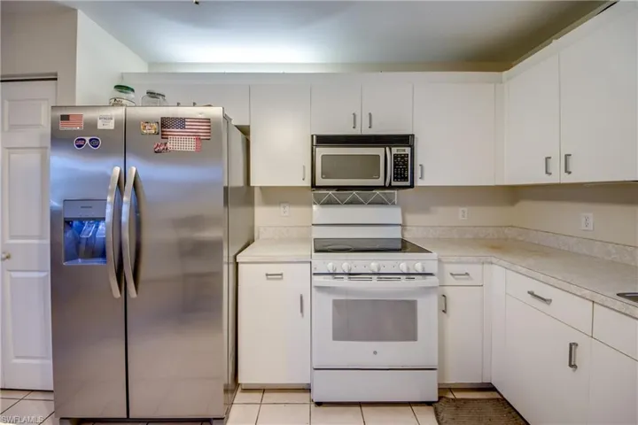 Kitchen featuring stainless steel appliances, white cabinetry, light countertops, and light tile patterned flooring