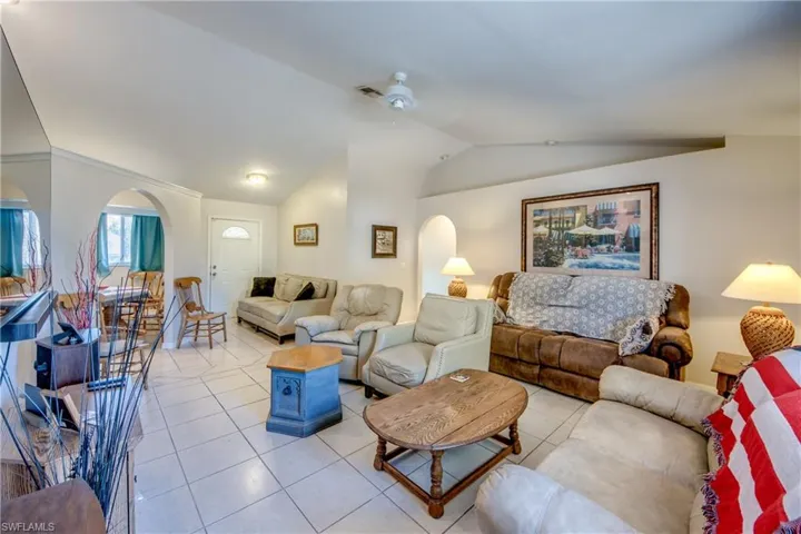 Tiled living area with arched walkways, vaulted ceiling, and ceiling fan