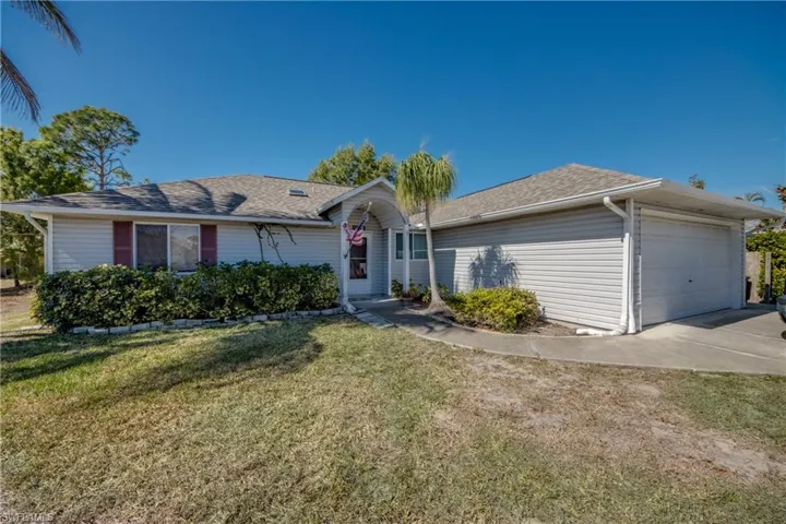 Ranch-style home with a shingled roof, a front yard, an attached garage, and concrete driveway