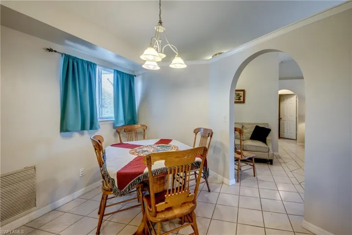 Dining area featuring hanging lights, tile patterned flooring, and ornamental molding