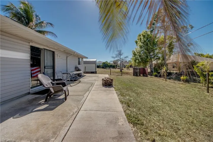 View of green lawn with a patio area and a storage shed