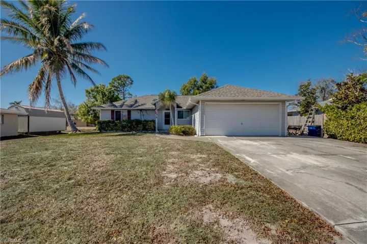 Ranch-style house with a garage, driveway, a front yard, and roof with shingles