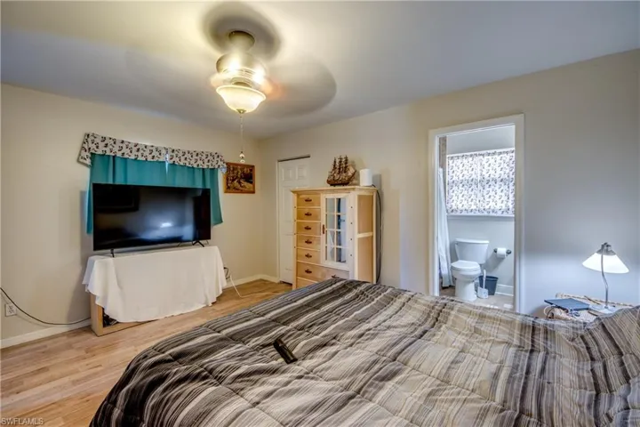 Bedroom featuring wood finished floors, a ceiling fan, and connected bathroom