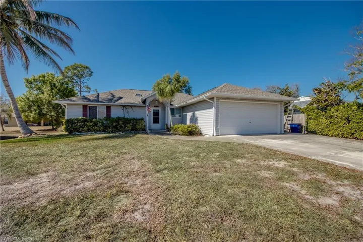 Ranch-style house featuring an attached garage, a front yard, concrete driveway, and roof with shingles
