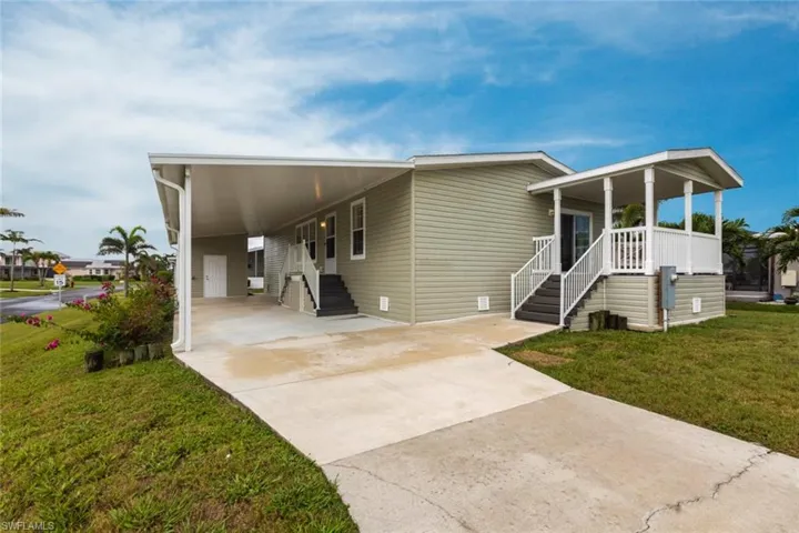 Manufactured / mobile home with a carport, a front yard, driveway, and a porch