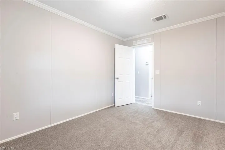Carpeted spare room with ornamental molding and baseboards