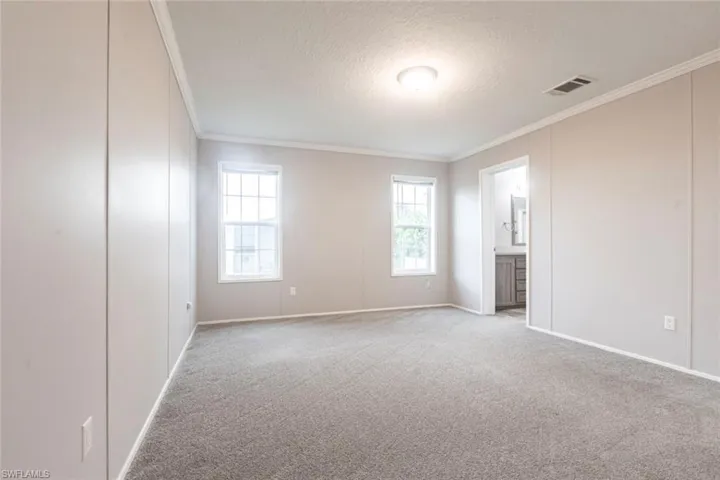 Unfurnished bedroom featuring ornamental molding, a textured ceiling, carpet, and connected bathroom
