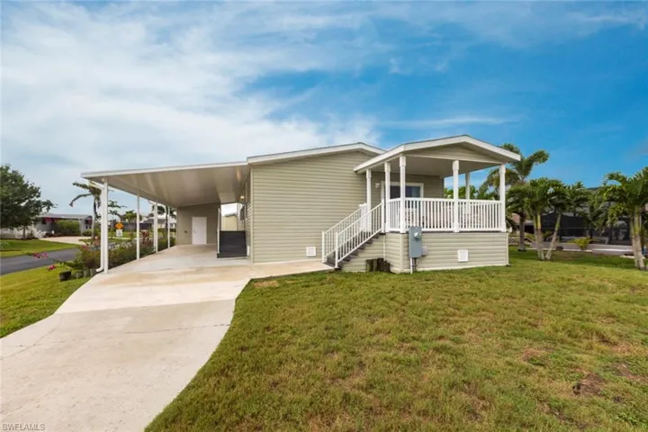 Manufactured / mobile home featuring a carport, driveway, a front lawn, and covered porch