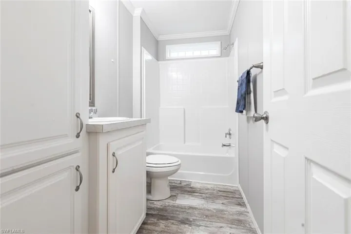 Full bath with vanity, crown molding, light wood-style flooring, and  shower combination