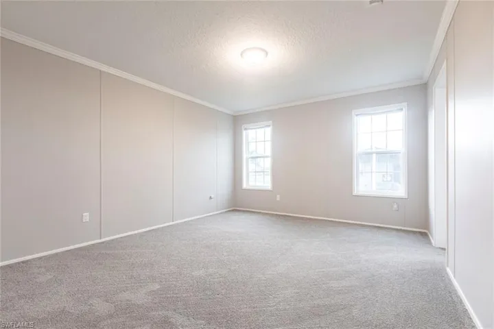 Carpeted spare room with crown molding and a textured ceiling