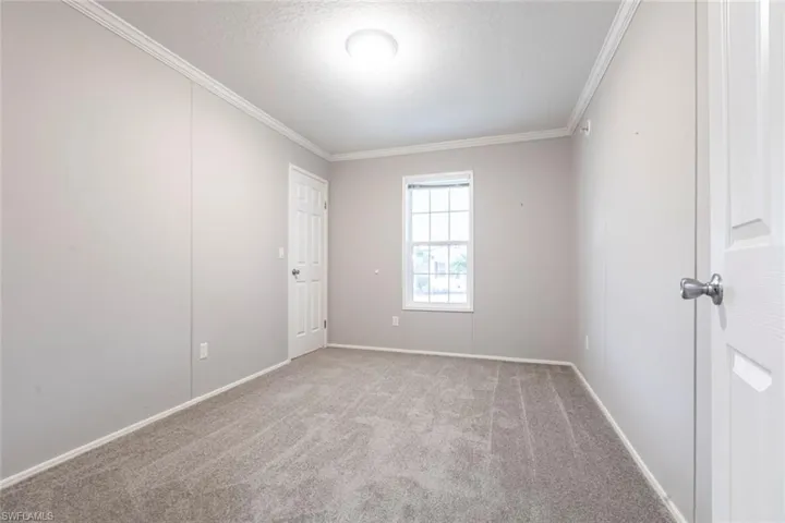 Empty room featuring a textured ceiling, crown molding, and carpet