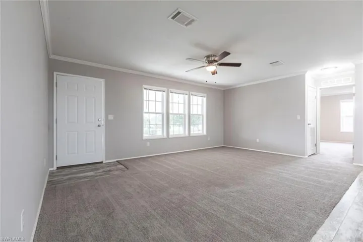 Unfurnished room featuring carpet flooring, a ceiling fan, and crown molding