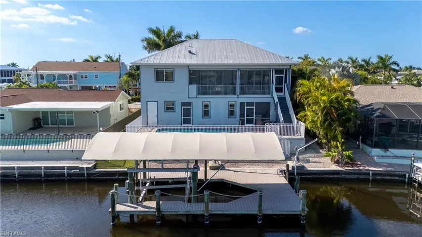 Rear view of house featuring a fenced backyard, an outdoor pool, a sunroom, and boat lift
