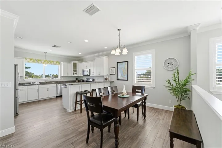 Dining area with ornamental molding, a chandelier, healthy amount of natural light, light wood finished floors, and recessed lighting