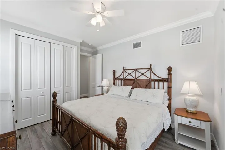 Bedroom with crown molding, dark wood finished floors, a closet, and a ceiling fan