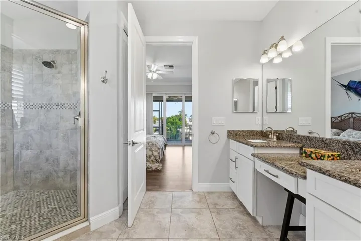 Ensuite bathroom with vanity, light tile patterned floors, a stall shower, ornamental molding, and ceiling fan