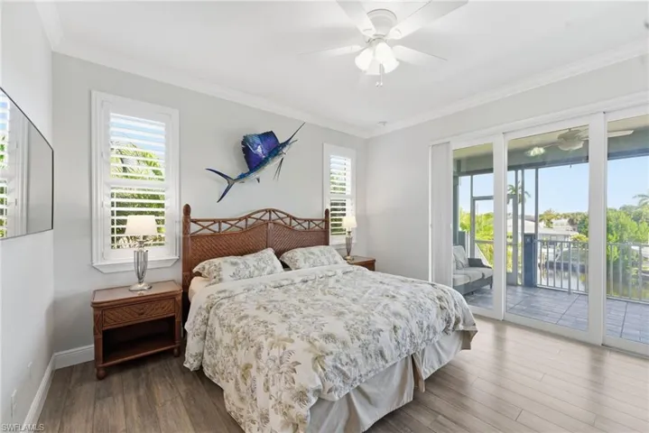 Bedroom with crown molding, multiple windows, access to exterior, wood finished floors, and a ceiling fan