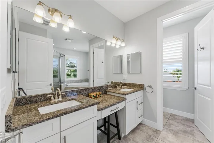 Full bath with a stall shower, a garden tub, double vanity, and healthy amount of natural light