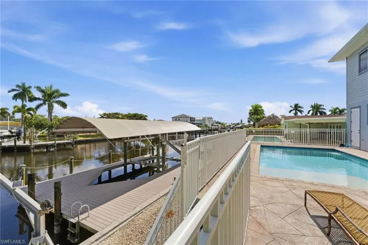 View of swimming pool featuring boat lift, a boat dock, a patio area, and a water view