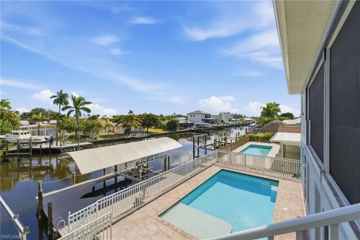 View of swimming pool featuring boat lift, a boat dock, and a water view