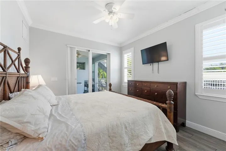 Bedroom featuring crown molding, wood finished floors, a ceiling fan, and access to outside