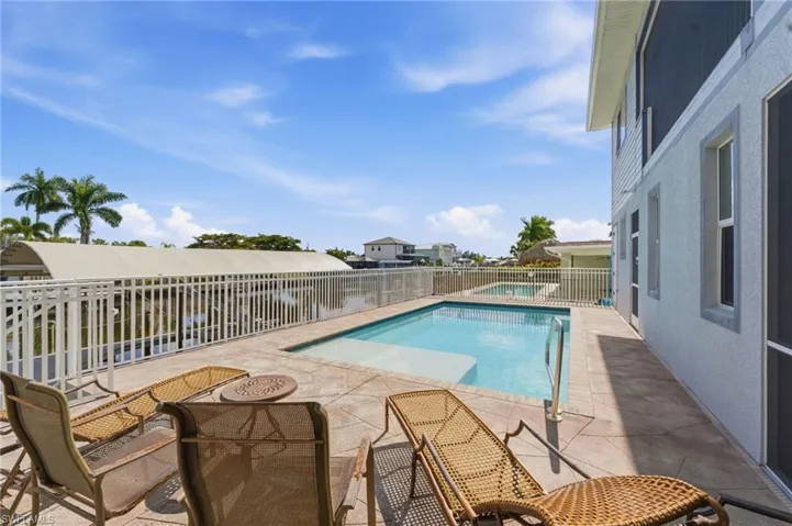 View of swimming pool featuring a patio, a water view, and a fenced backyard