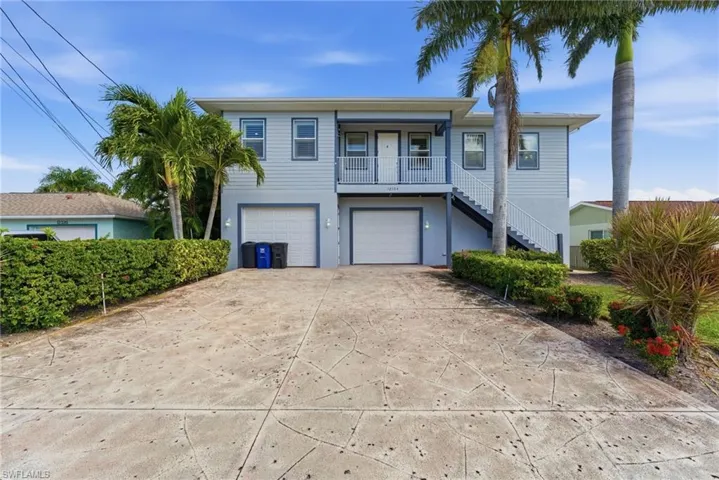 Coastal home with stairway, driveway, and an attached garage