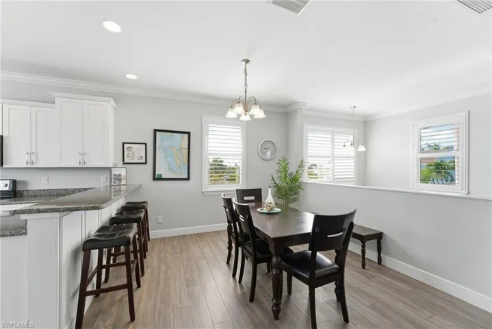 Dining area with ornamental molding, light wood-type flooring, plenty of natural light, a chandelier, and recessed lighting