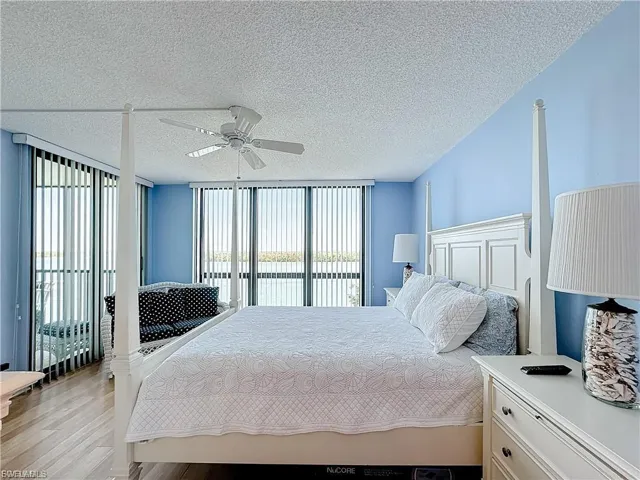 Bedroom with floor to ceiling windows, a textured ceiling, wood finished floors, ceiling fan, and access to outside