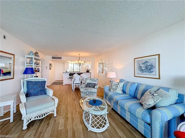 Living area with a textured ceiling, wood finished floors, and a chandelier