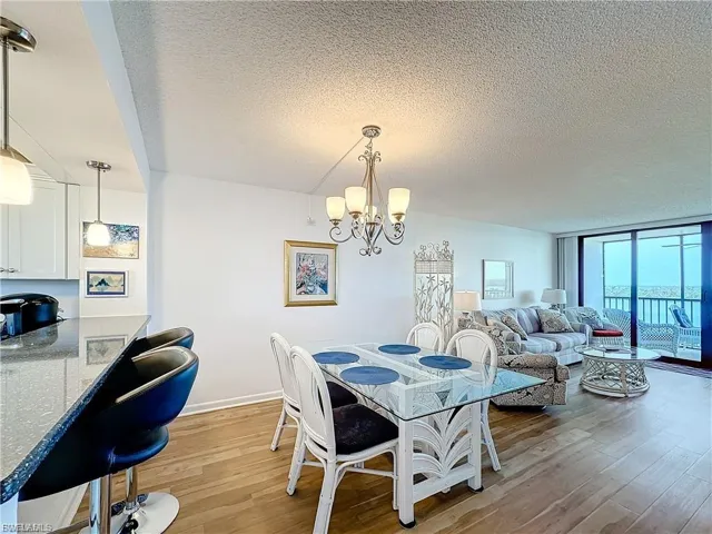 Dining room with a textured ceiling, light wood-type flooring, a chandelier, and floor to ceiling windows