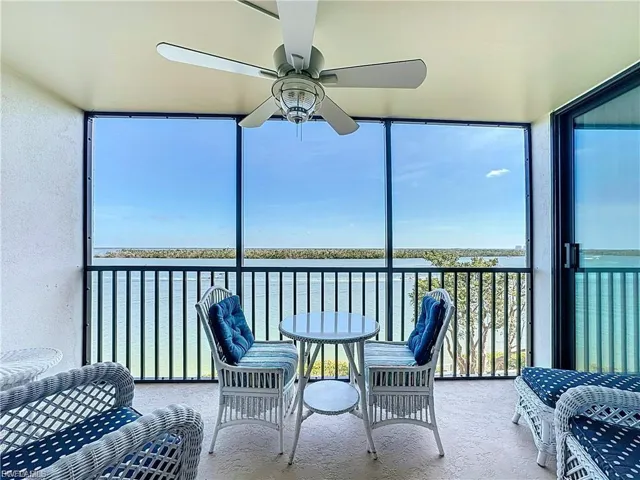 Sunroom / solarium with a ceiling fan, a water view, and a balcony