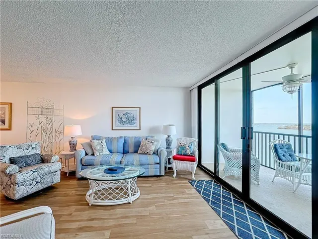 Living room with wood finished floors, expansive windows, a water view, and a textured ceiling